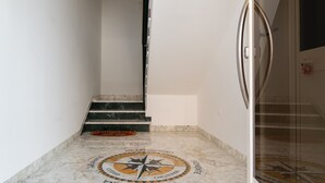 Ein Flur mit Marmorboden, einem Kompassmuster, einer Treppe und einer Glastür.