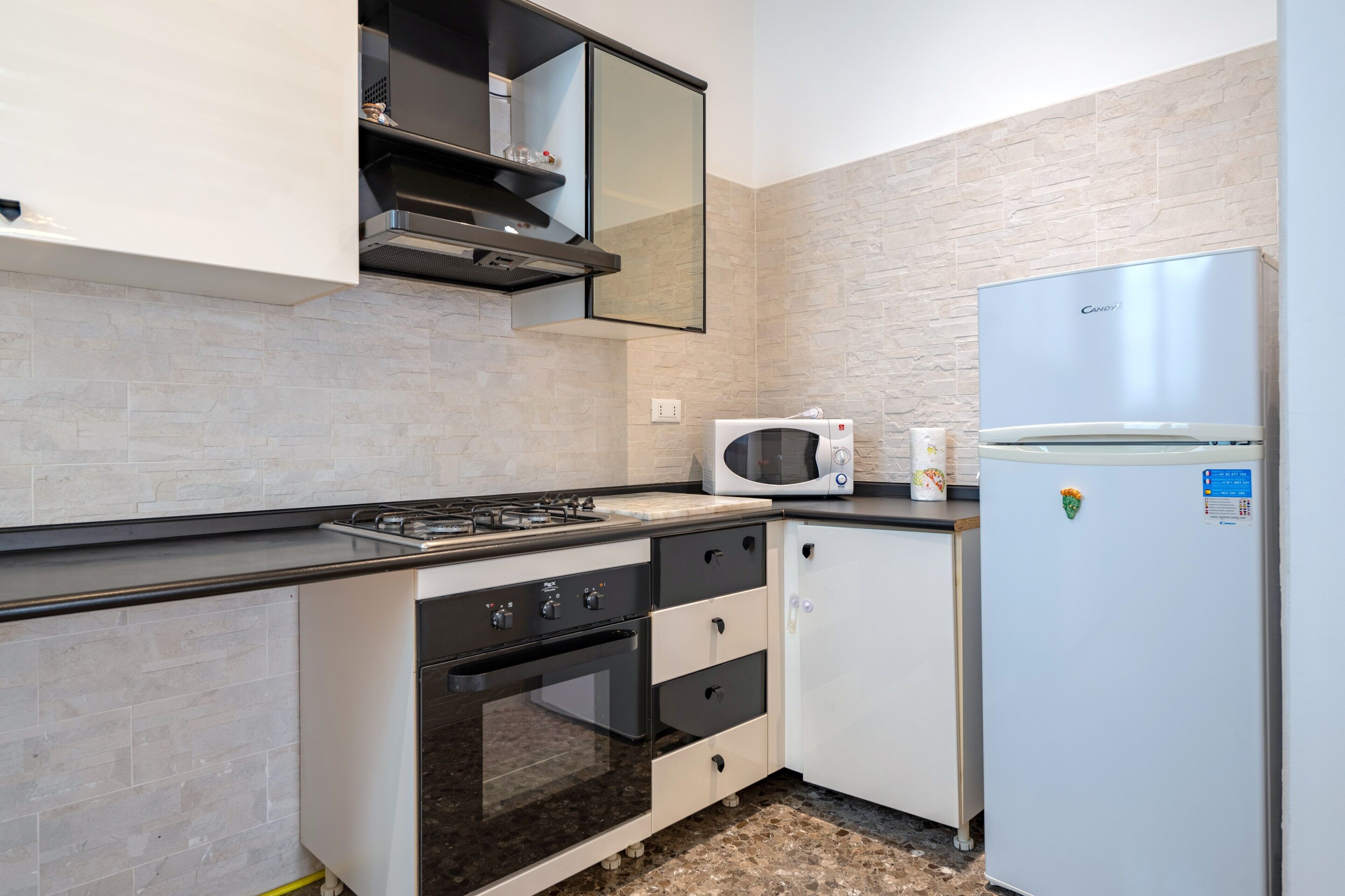 Una cocina compacta con estufa a gas, horno, microondas y refrigerador.