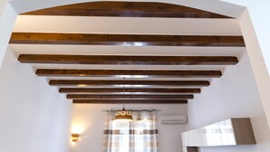Eine Treppe mit Holzbalken, einer Hängeleuchte und einem Fenster mit Vorhängen.