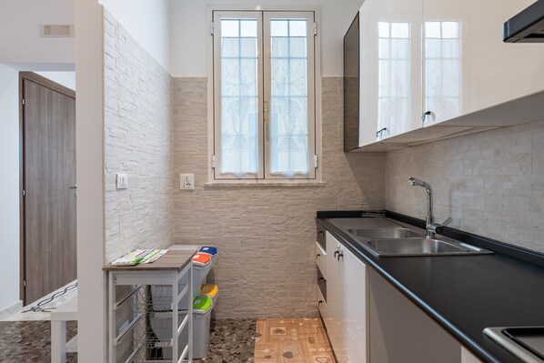 A compact kitchen with a window, a sink, and a small table with storage containers. - Holiday Home "Rosa Dei Venti" - Grottaglie (Grottaglie)