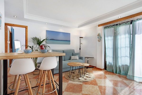 A modern living room with a sofa, a coffee table, and a dining area with chairs and a table.