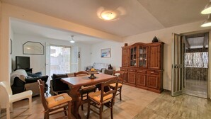 A dining area with a wooden table and chairs, a television, and a cabinet. - Apartment 'Casa Alamar' with Private Garden, Wi-Fi and Air Conditioning (Alcamo)