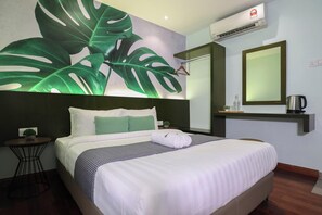Una habitación de hotel con una cama, una mesita de noche, una pequeña mesa con una planta, un espejo grande y un equipo de aire acondicionado.