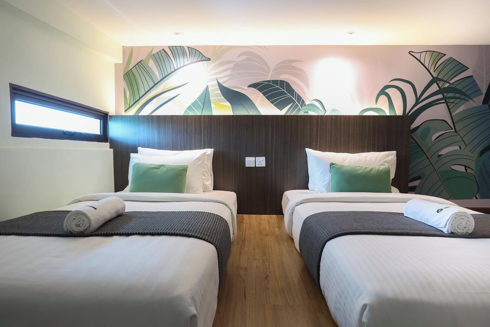 Une chambre d’hôtel avec deux lits, une grande fenêtre et une fresque murale.