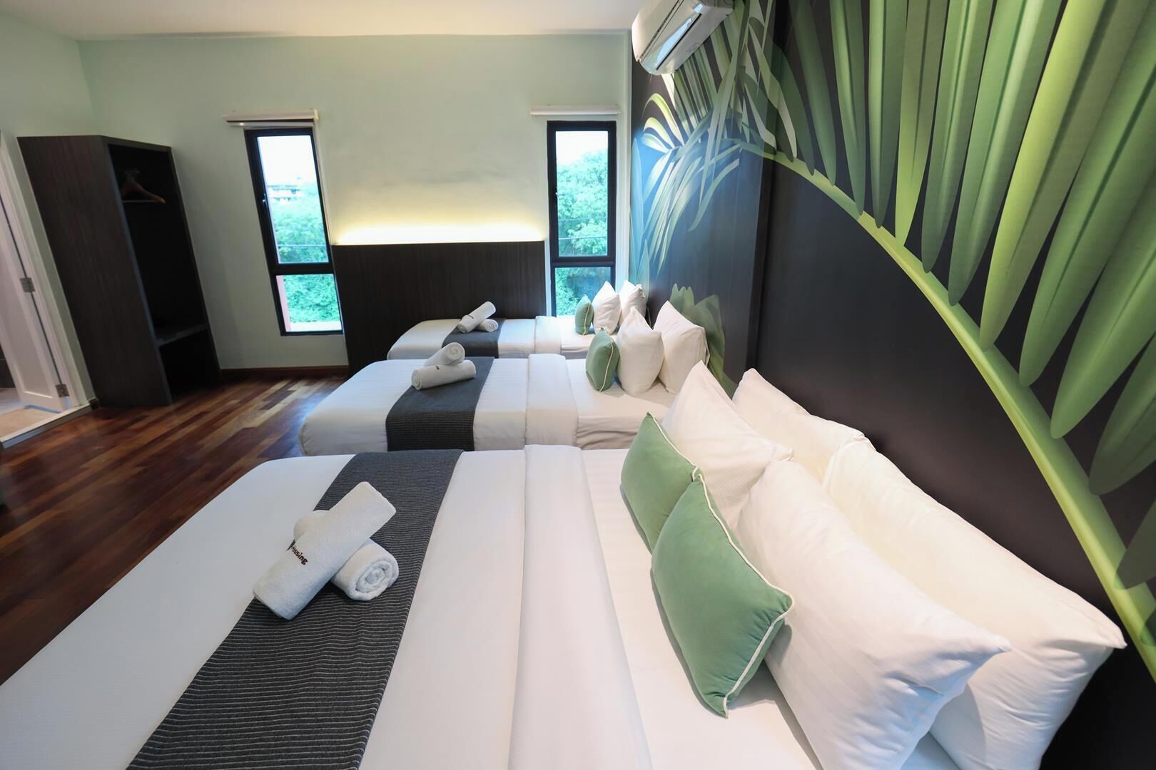 A hotel room with two beds, a wardrobe, and a large window.