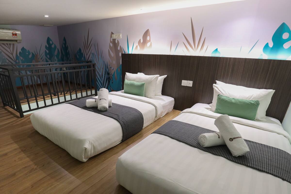 A hotel room with two beds, a crib, and a wall mural.