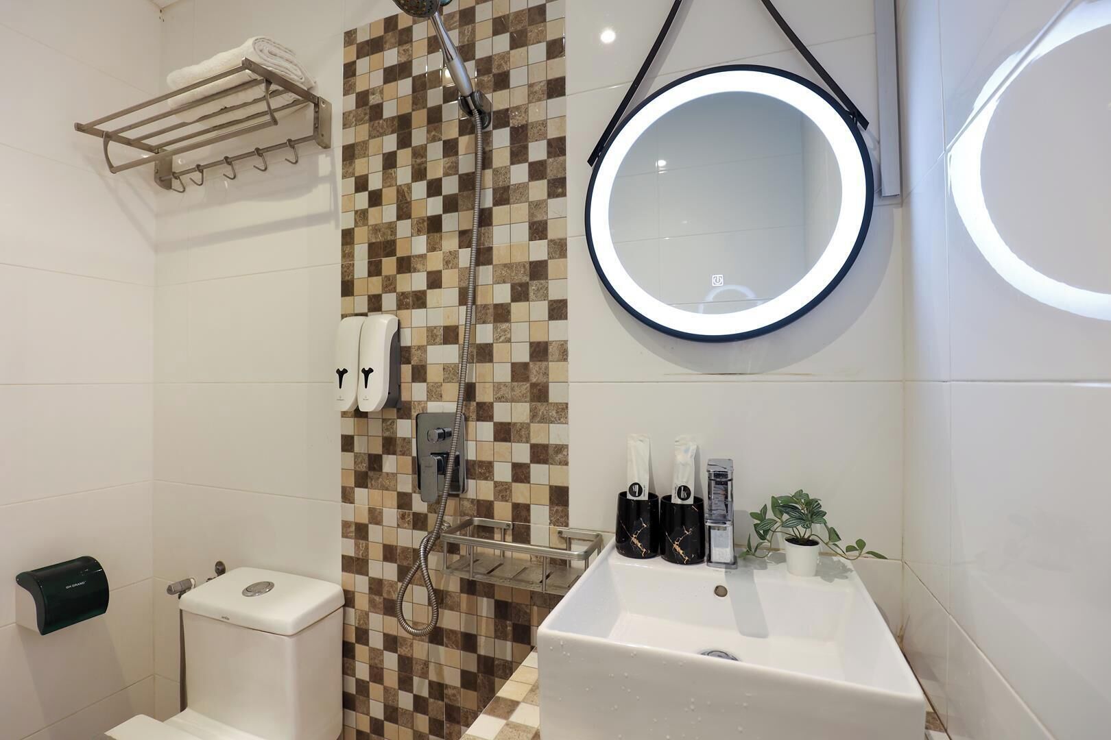 Baño con ducha, inodoro, lavamanos y espejo con luz.