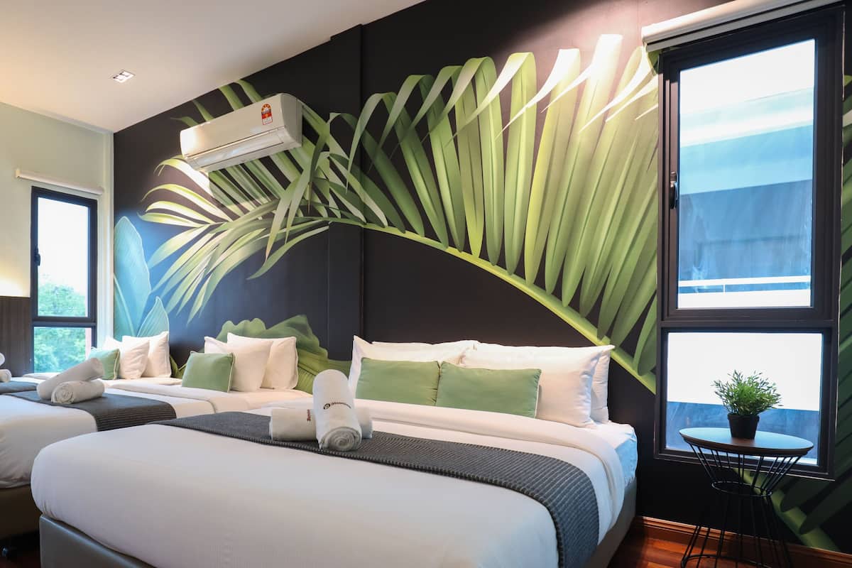 A hotel room with two beds, a large window, an air conditioning unit, and a potted plant.