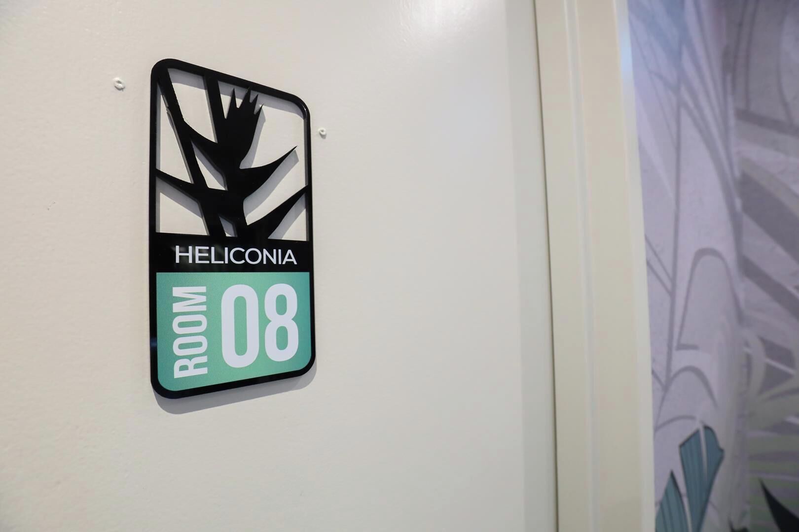 En skylt för Heliconia, rum 08, med en stiliserad svartvit logotyp.