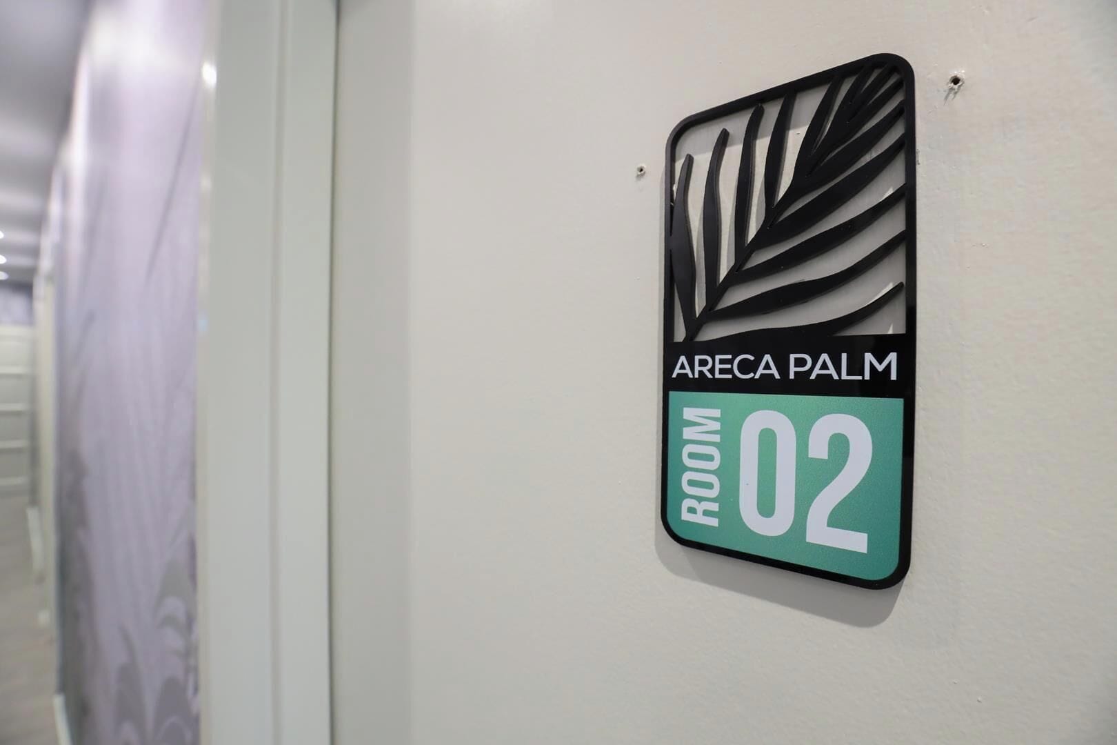 Segnaletica che indica 'ARECA PALM ROOM 02' su una parete bianca.