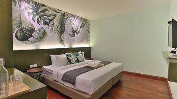 Quarto moderno com uma cama grande, uma mesa de cabeceira, televisão fixada na parede e um mural com folhagem tropical.