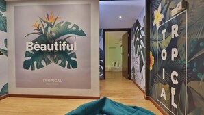 A hallway with a tropical-themed wall mural, a bed, and a wooden floor. - Trevor Hotel by I Housing (Malacca City)