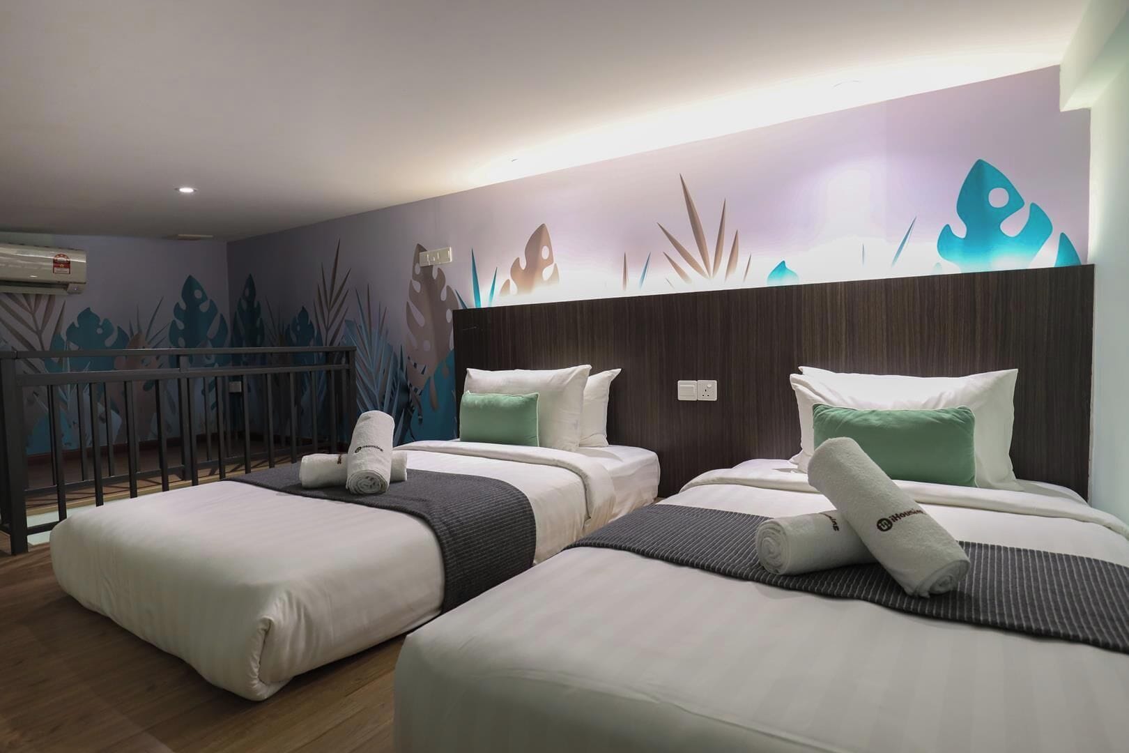 Habitación de hotel con dos camas, un balcón y una pared decorada con un diseño de hojas.