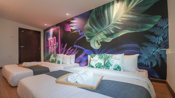 A hotel room with two beds, a large tropical-themed mural, and a wooden door. - Trevor Hotel by I Housing (Malacca City)