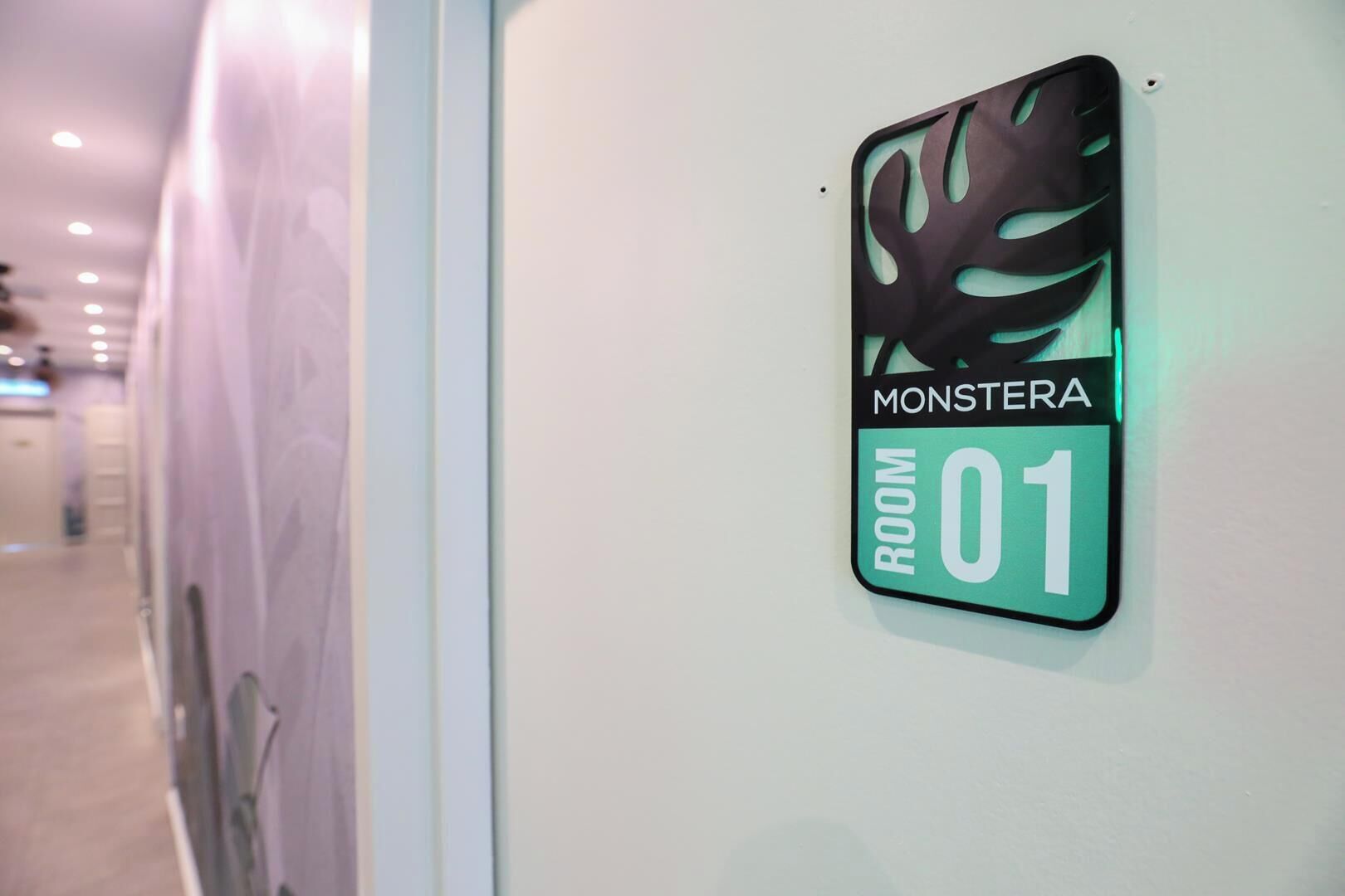 A sign indicating 'MONSTERA ROOM 01' on a wall.