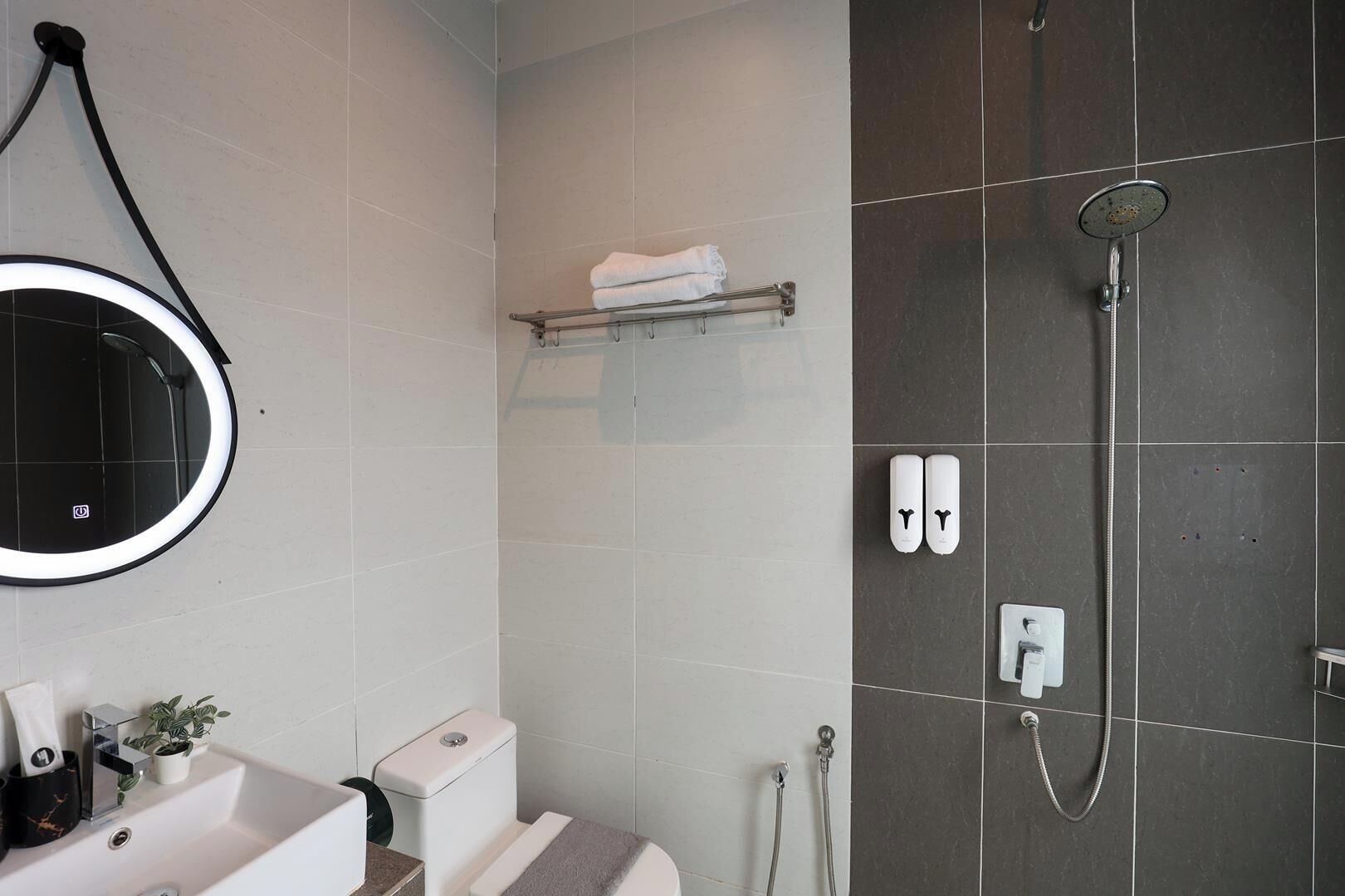 Een badkamer met douche, toilet, wastafel en handdoekhouder.