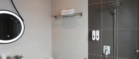 Een badkamer met douche, toilet, wastafel en handdoekhouder.