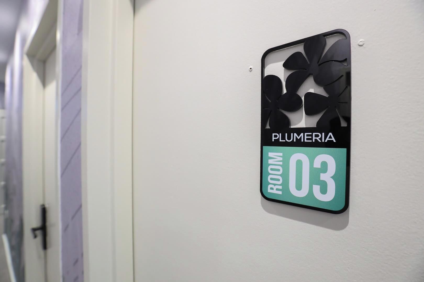A sign indicating 'PLUMERIA ROOM 03' on a wall.