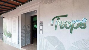 A hotel entrance with a sign reading 'The Tropics' and a glass door leading inside. - Trevor Hotel by I Housing (Malacca City)