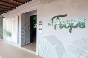 A hotel entrance with a sign reading 'The Tropics' and a glass door leading inside. - Trevor Hotel by I Housing (Malacca City)