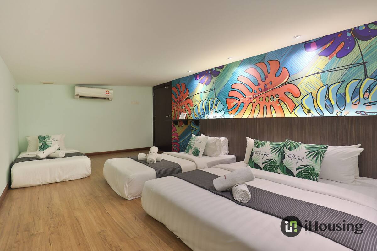 A hotel room with a large bed, two smaller beds, a wall mural, and a wooden floor.
