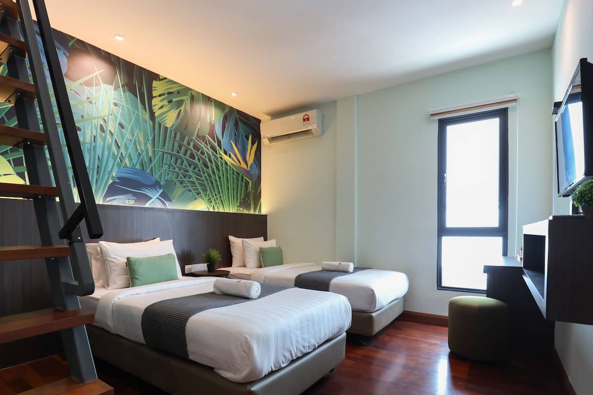 A modern hotel room with a large bed, a smaller bed, a desk, and a window.