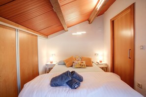 Une chambre à coucher avec un lit, des oreillers, une table de chevet avec une lampe et une armoire.