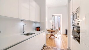 A modern kitchen with white cabinets, a stainless steel sink, and a built-in oven. - Villa 'Casa Rosa' with Private Terrace and Wi-Fi (São Brás de Alportel)