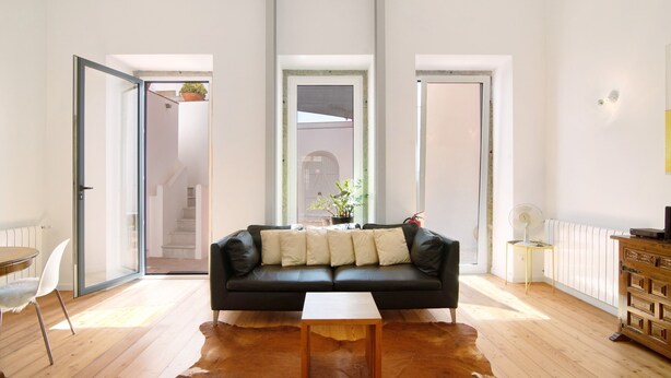 A modern living room with a black leather sofa, a wooden coffee table, and a cowhide rug. - Villa 'Casa Rosa' with Private Terrace and Wi-Fi (São Brás de Alportel)