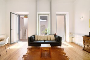 A modern living room with a black leather sofa, a wooden coffee table, and a cowhide rug. - Villa 'Casa Rosa' with Private Terrace and Wi-Fi (São Brás de Alportel)