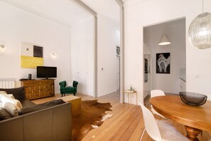 Una sala de estar moderna con un sofá, televisión y un comedor con mesa y sillas.
