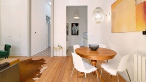 A dining area with a round wooden table, white chairs, a hanging light fixture, and a cowhide rug. - Villa 'Casa Rosa' with Private Terrace and Wi-Fi (São Brás de Alportel)