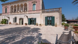 Un edifici amb un pati interior, una banca de fusta i plantes en testos.