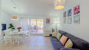 Una sala moderna con un sofá, una mesa de comedor, sillas y un televisor.