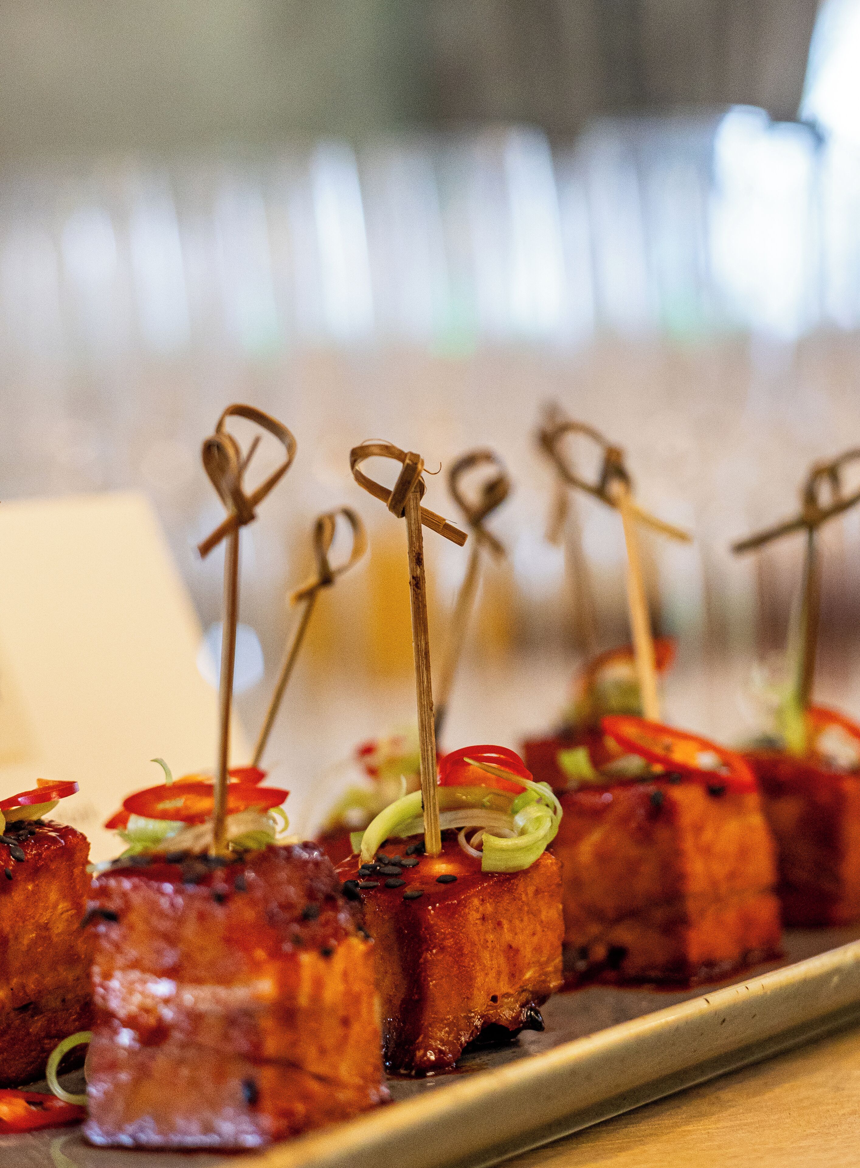 A tray of appetizers with skewers, garnished with vegetables and sauce.