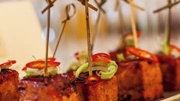 A tray of appetizers with skewers, garnished with vegetables and sauce.