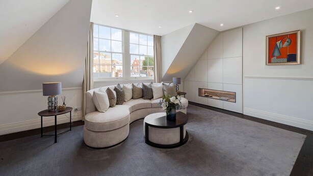 Un salon moderne avec un canapé d’angle aux lignes courbes, une table basse ronde et une cheminée.
