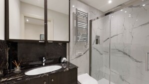 Une salle de bain moderne avec un lavabo en marbre, un grand miroir, une douche en verre et des toilettes.