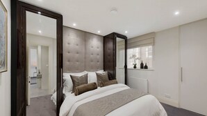 Une chambre avec un grand lit, une armoire, un miroir et une vue sur une autre pièce.