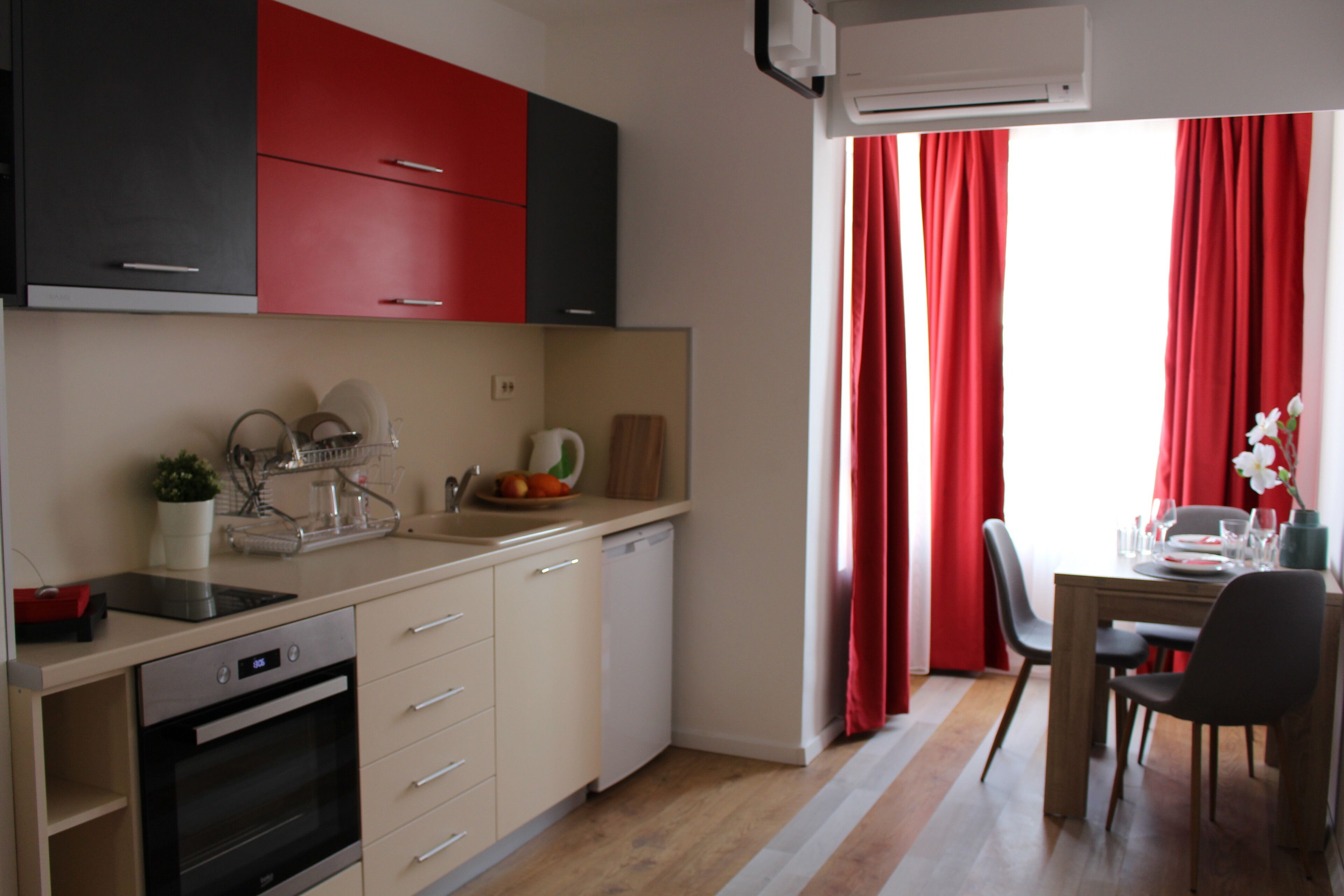 A modern kitchen with a dishwasher, oven, and a dining area with a table and chairs.