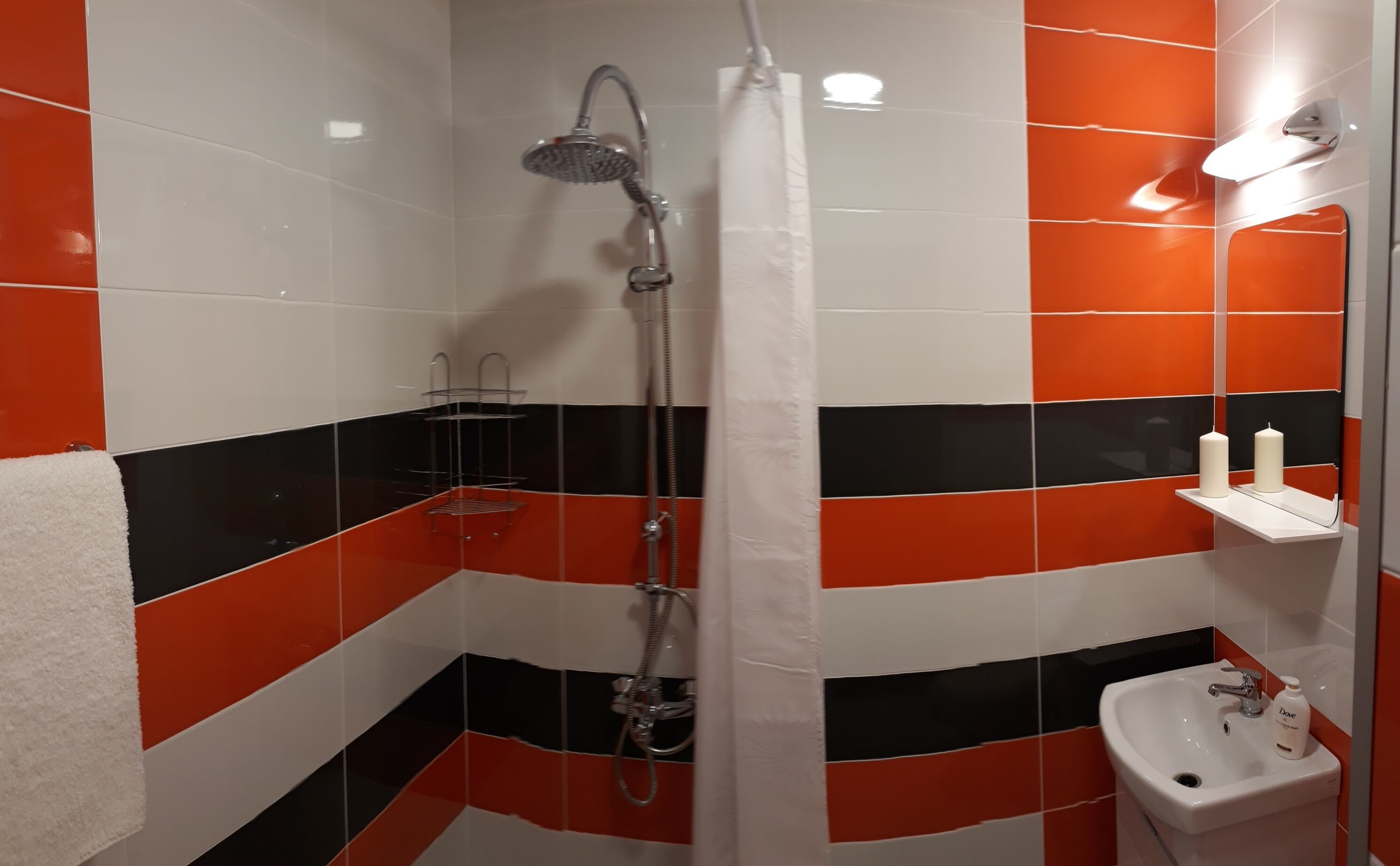 A bathroom with a shower, a sink, and a towel rack.
