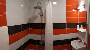 A bathroom with a shower, a sink, and a towel rack.