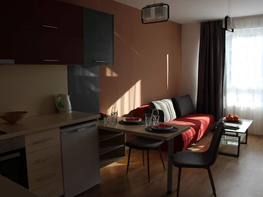 Una cocina moderna con lavavajillas, un comedor con mesa y sillas, un sofá y una ventana con cortinas.