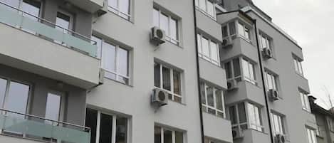 A multi-story residential building with balconies, air conditioning units, and a modern architectural style.