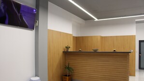 A reception desk with a wooden finish, a potted plant, and a trash bin. - HOTEL39 (Plovdiv)