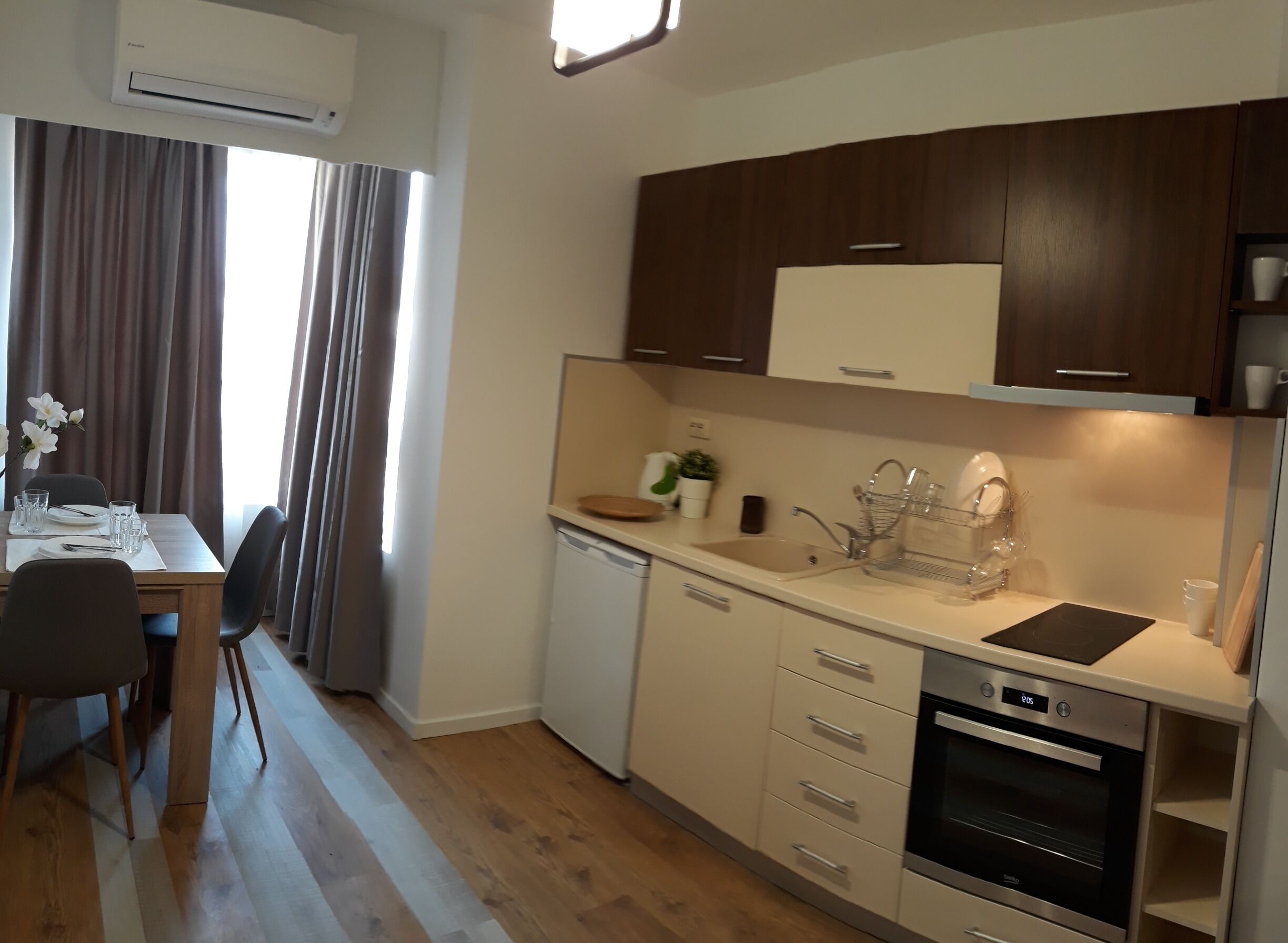A modern kitchen with a dishwasher, oven, and a dining area with a table set for two.