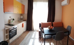 A compact kitchen with a modern oven, a sink, and a dining area with a table and chairs.