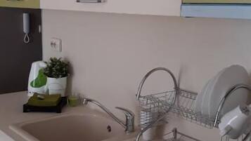 A kitchen with a sink, dish rack, and cabinets.