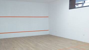 A room with white walls and a wooden floor marked with orange lines, likely for a game or activity.