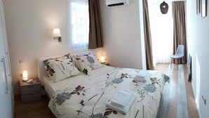 A neatly made bed with floral bedding, a bedside lamp, and a nightstand with a lamp. - HOTEL39 (Plovdiv)